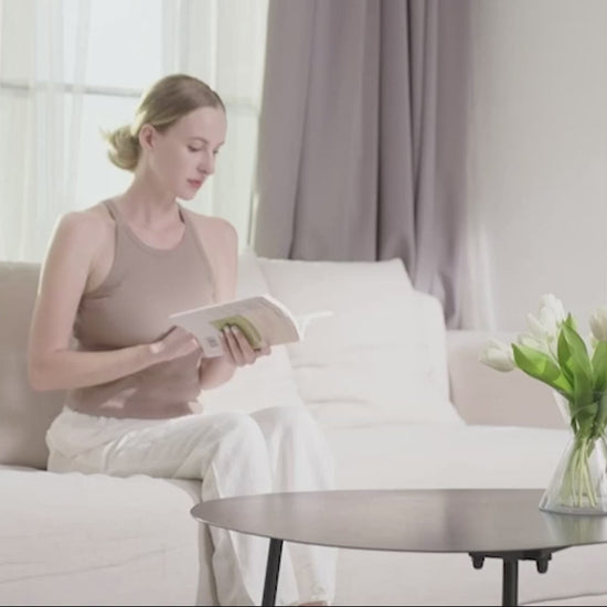Woman relaxing on a sofa while using a shiatsu neck and back massager with deep tissue and heating features for soothing relief