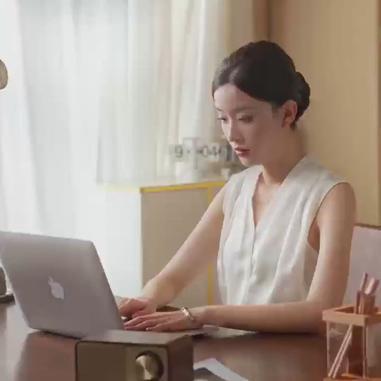 A woman using a laptop at a stylish desk in a well-lit home office, showcasing an inviting workspace atmosphere.