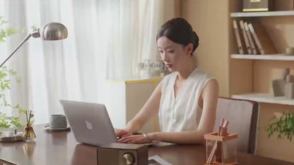 A woman using a laptop at a stylish desk in a well-lit home office, showcasing an inviting workspace atmosphere.